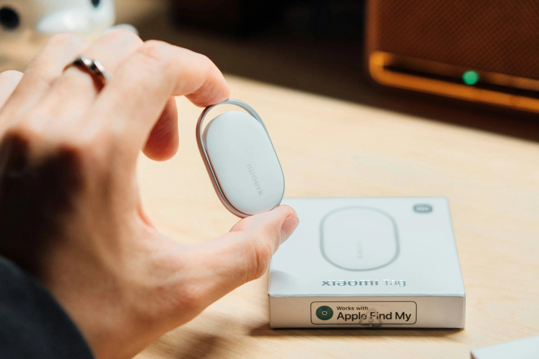 Hand holding a white tracking device next to its box